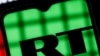Behind bars is a smartphone with the RT (Russia Today) logo on the background of the Youtube logo. Blocking RT (Russia Today) YouTube channels.